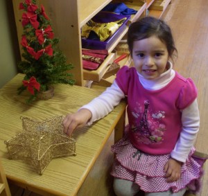 student poses proudly with her holiday practical life work