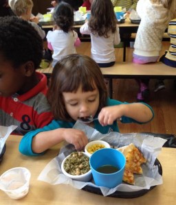 This wee one enjoys her lunch of pizza, tabouleh, and corn.
